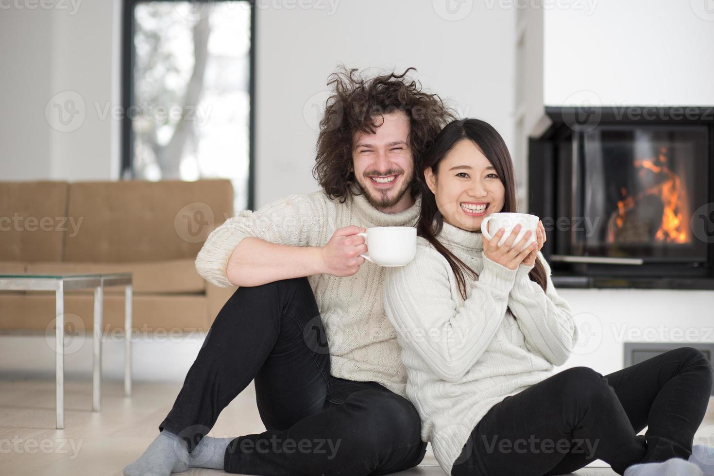 feliz casal multiétnico em frente à lareira foto