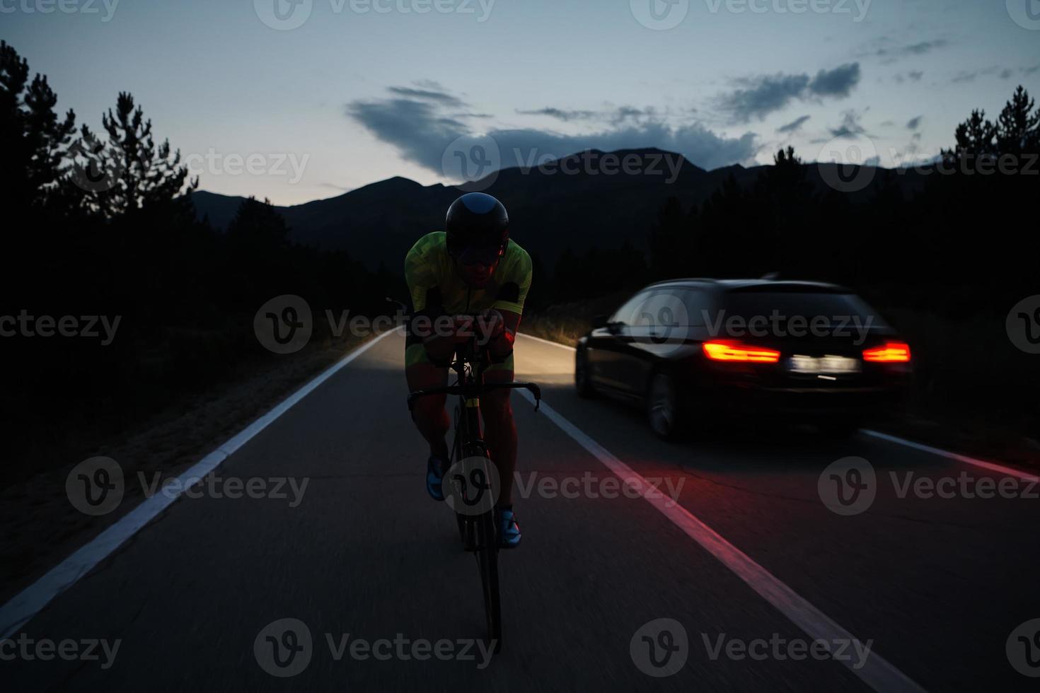 atleta de triatlo andando de bicicleta à noite foto