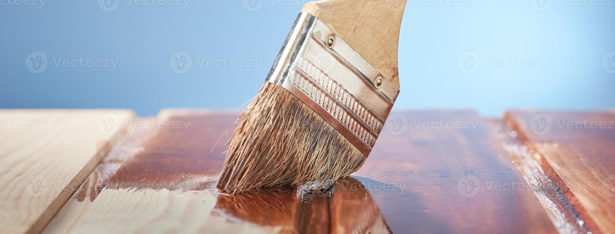 pintando piso de madeira com verniz protetor sobre fundo azul. foto