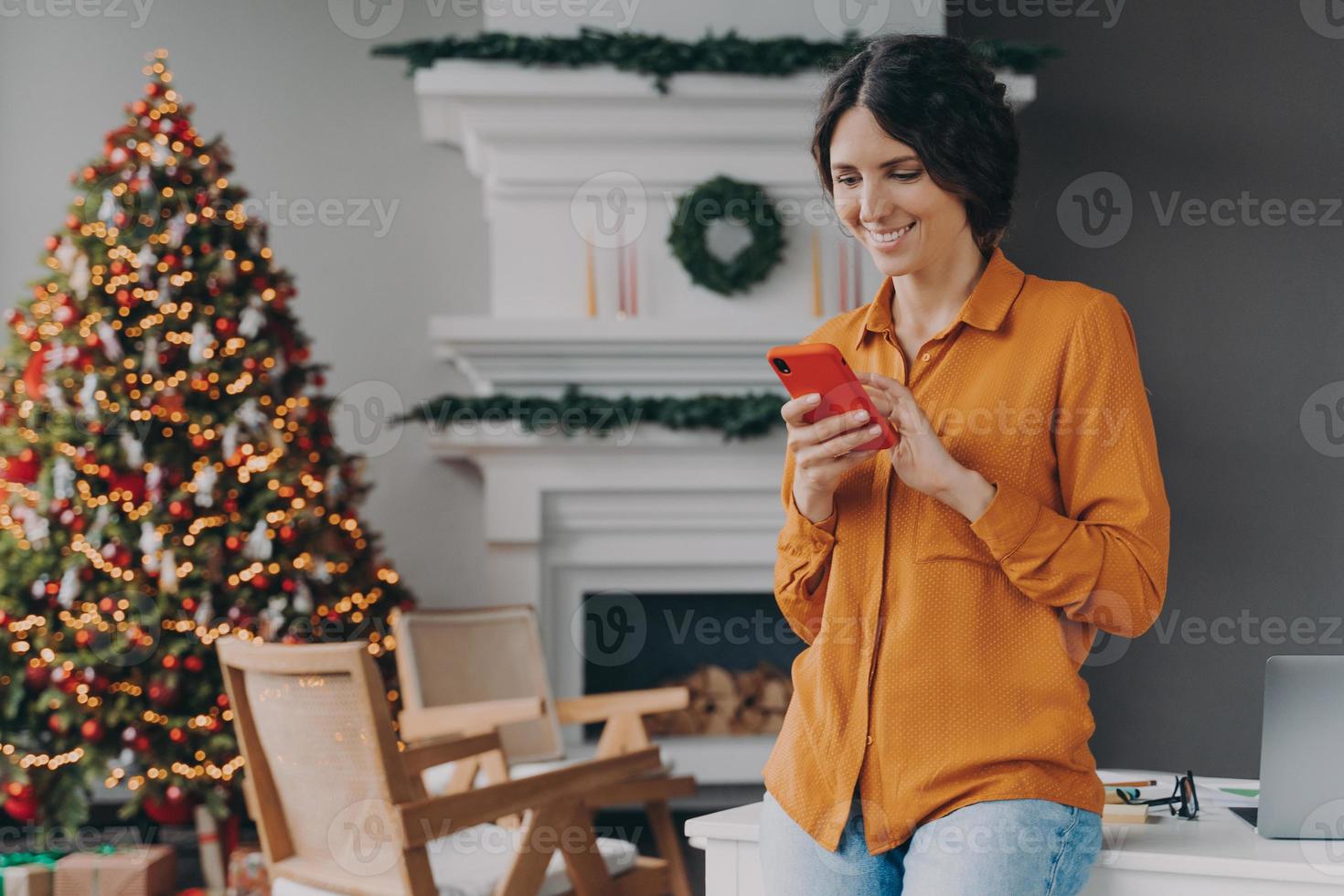 mulher feliz digitando no celular durante as férias de natal em casa foto