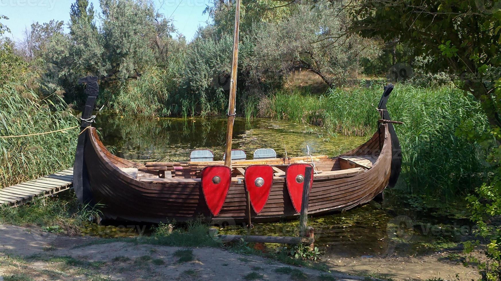 barco à vela, um pequeno navio de madeira na costa. transporte para reconstruções históricas e excursões para turistas. pitoresca marina para o fabuloso navio viking. barco vintage com mastro e remos foto