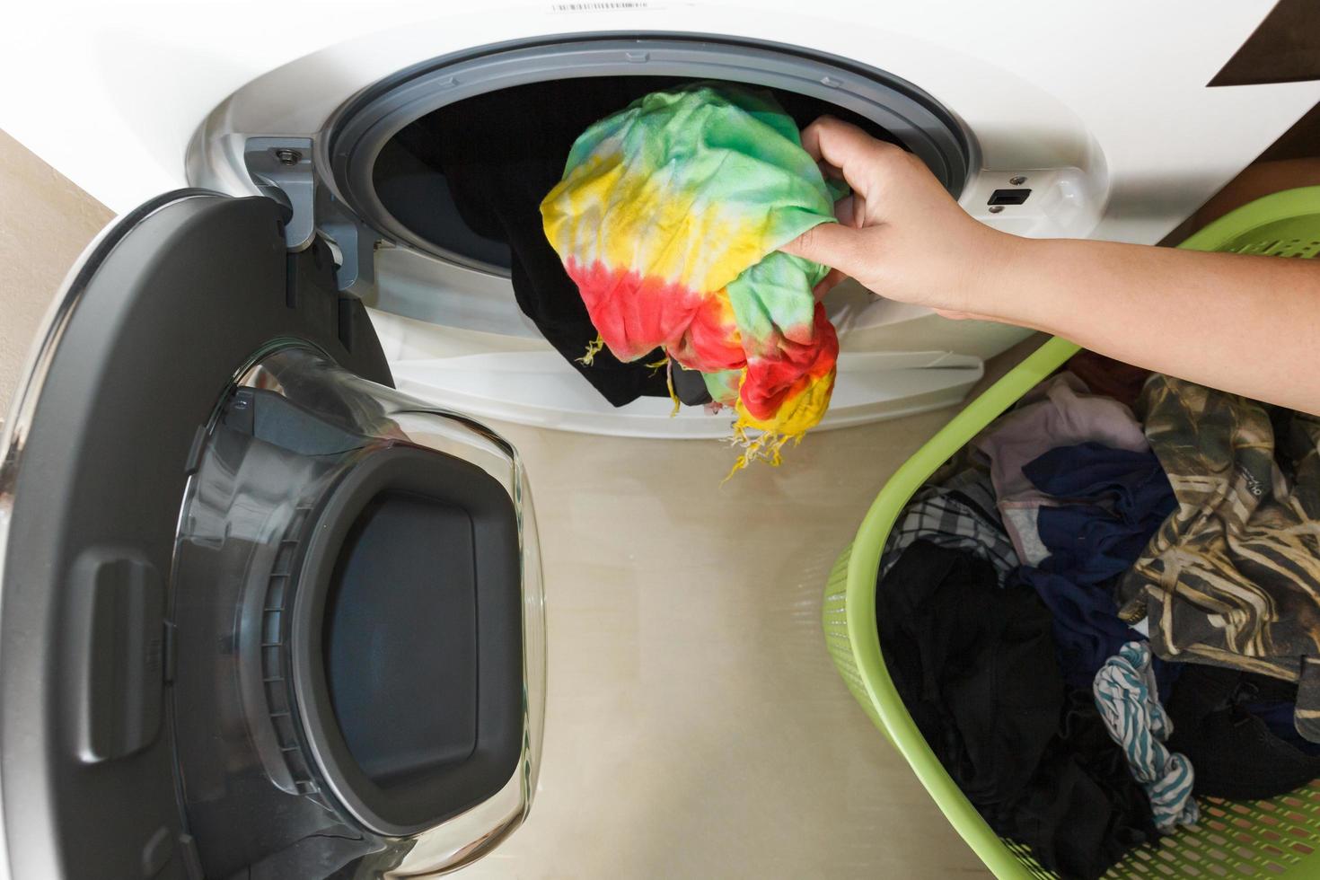 vista superior da mão de uma mulher colocando roupas sujas na máquina de lavar. foto