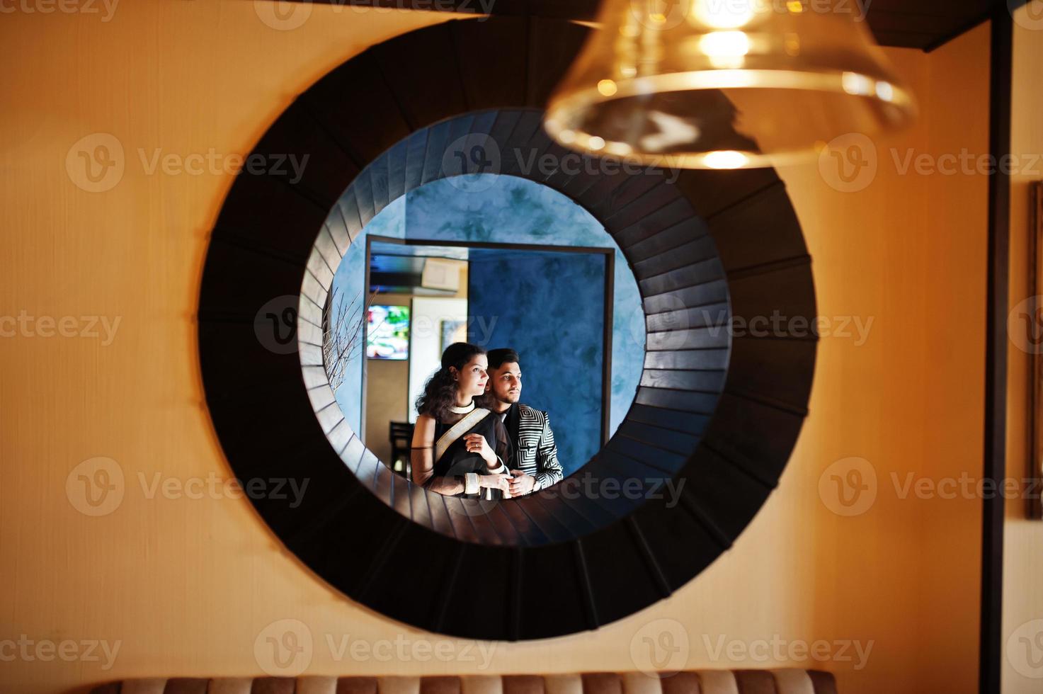 lindo casal indiano apaixonado, veste saree e terno elegante, posou no restaurante no círculo redondo na parede. foto