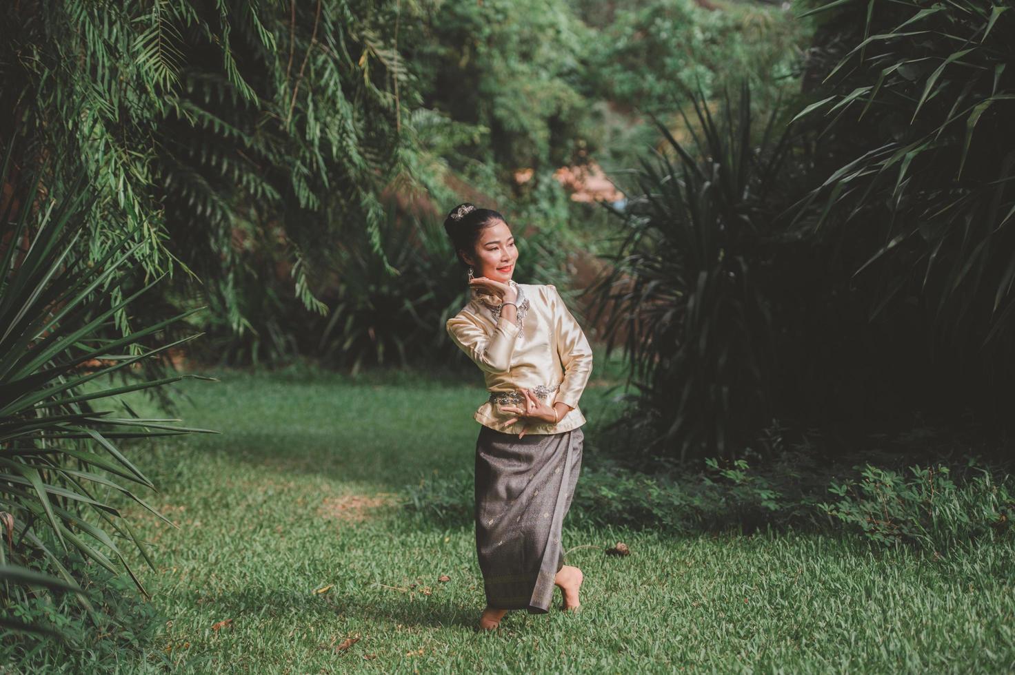 uma mulher vestindo um vestido tailandês com um sinal de mão foto