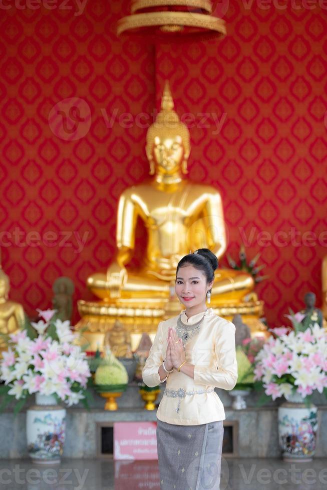 uma mulher vestindo roupas tailandesas em homenagem ao símbolo sawasdee. foto