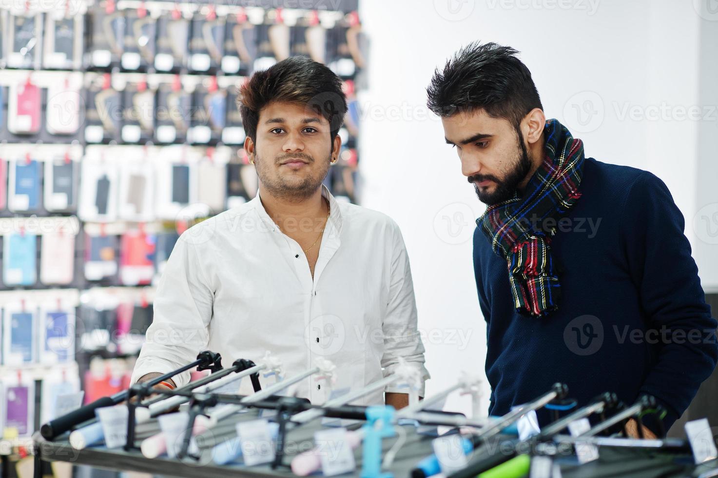 dois índios mans comprador do cliente na loja de telefones celulares escolhem um bastão de selfie. conceito de povos e tecnologias do sul da Ásia. loja de celulares. foto