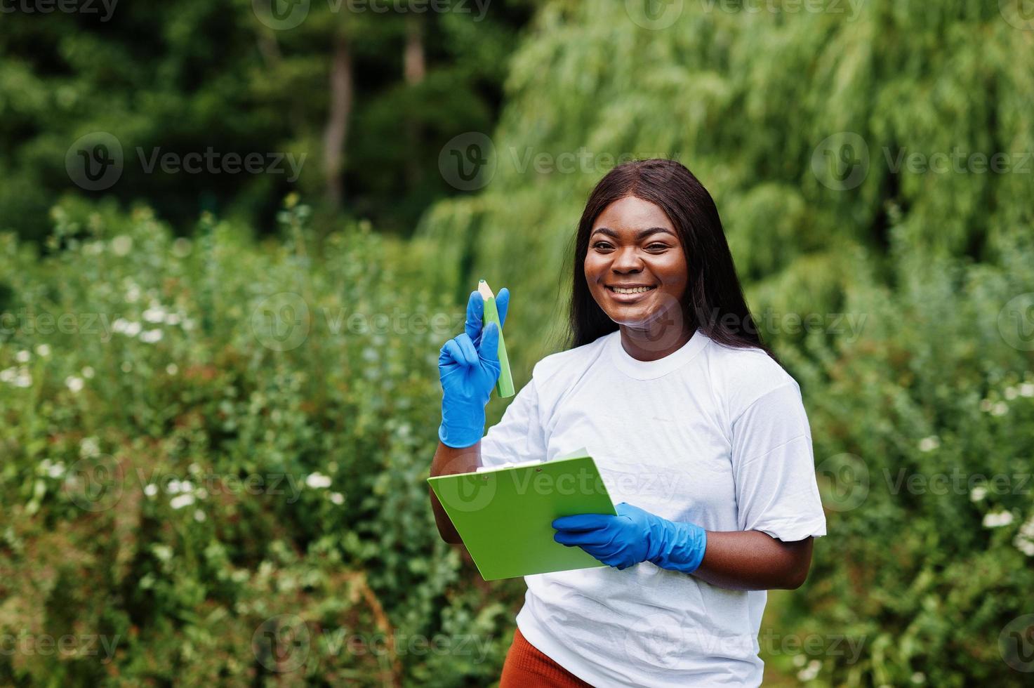 mulher voluntária africana com prancheta no parque. áfrica voluntariado, caridade, pessoas e conceito de ecologia. foto