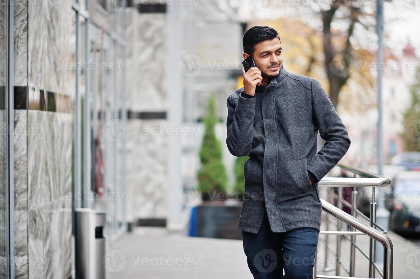 homem hindu indiano elegante com casaco cinza posou na rua e falando no  telefone. 10380604 Foto de stock no Vecteezy