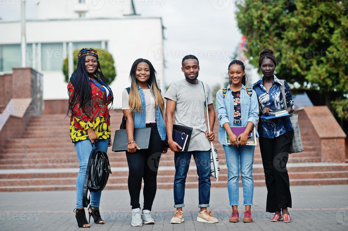 grupo de cinco estudantes universitários africanos passando tempo juntos no campus no pátio da universidade. amigos negros afro estudando. tema educação. foto