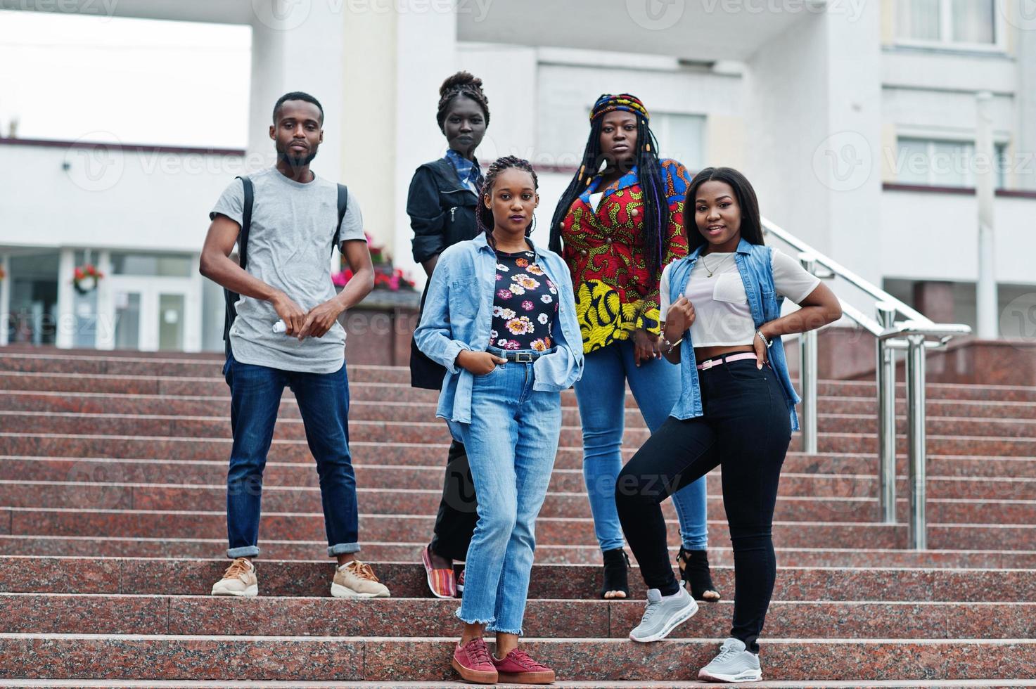 grupo de cinco estudantes universitários africanos passando tempo juntos no campus no pátio da universidade. amigos negros afro estudando. tema educação. foto