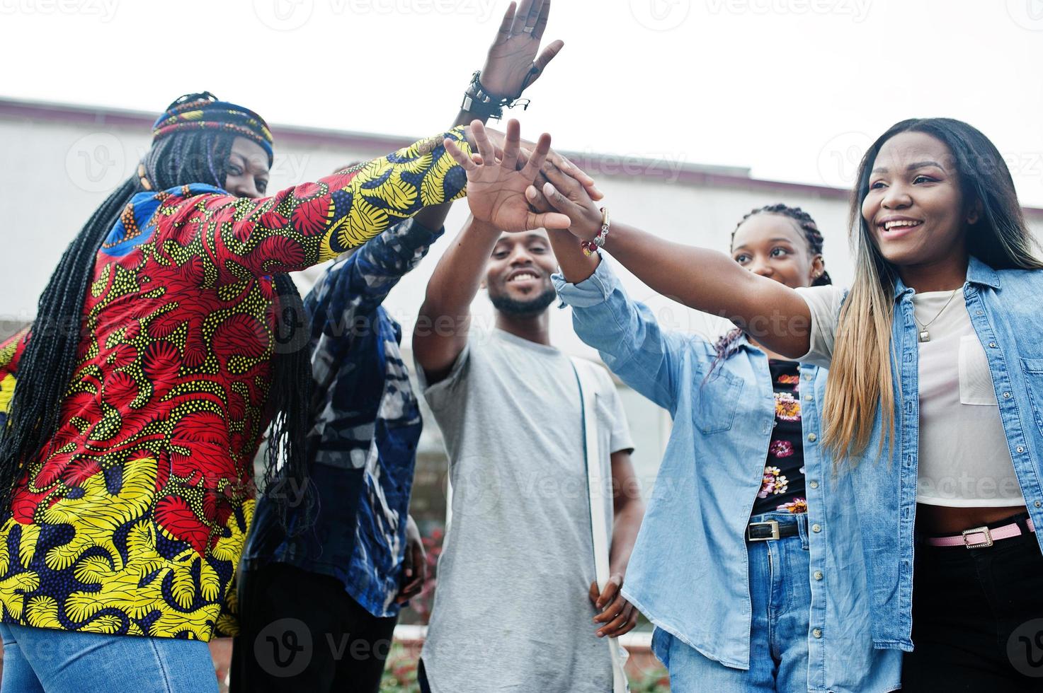 grupo de cinco estudantes universitários africanos passando tempo juntos no campus no pátio da universidade. amigos negros afro estudando. tema educação. mãos nas mãos. foto