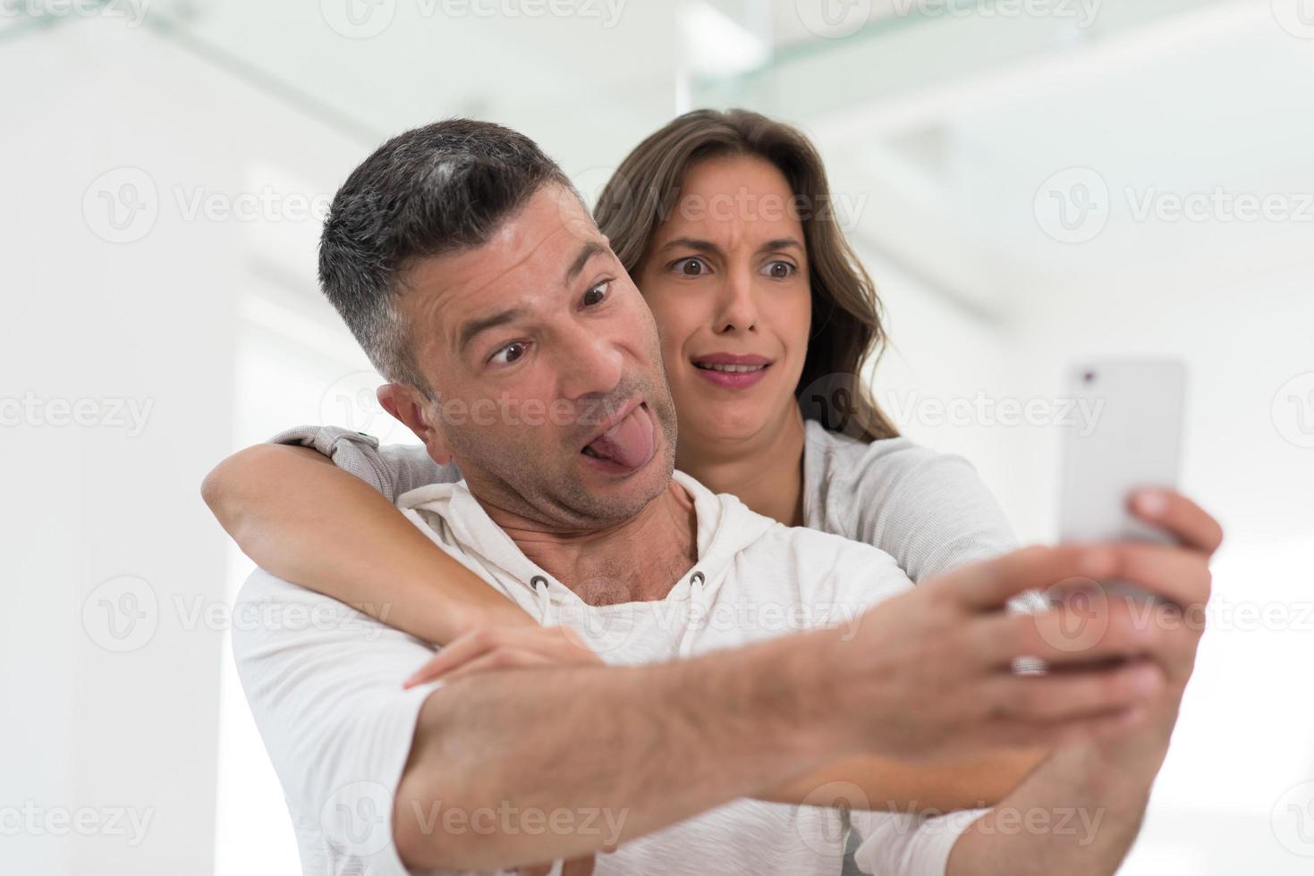 casal feliz usando celular em casa foto