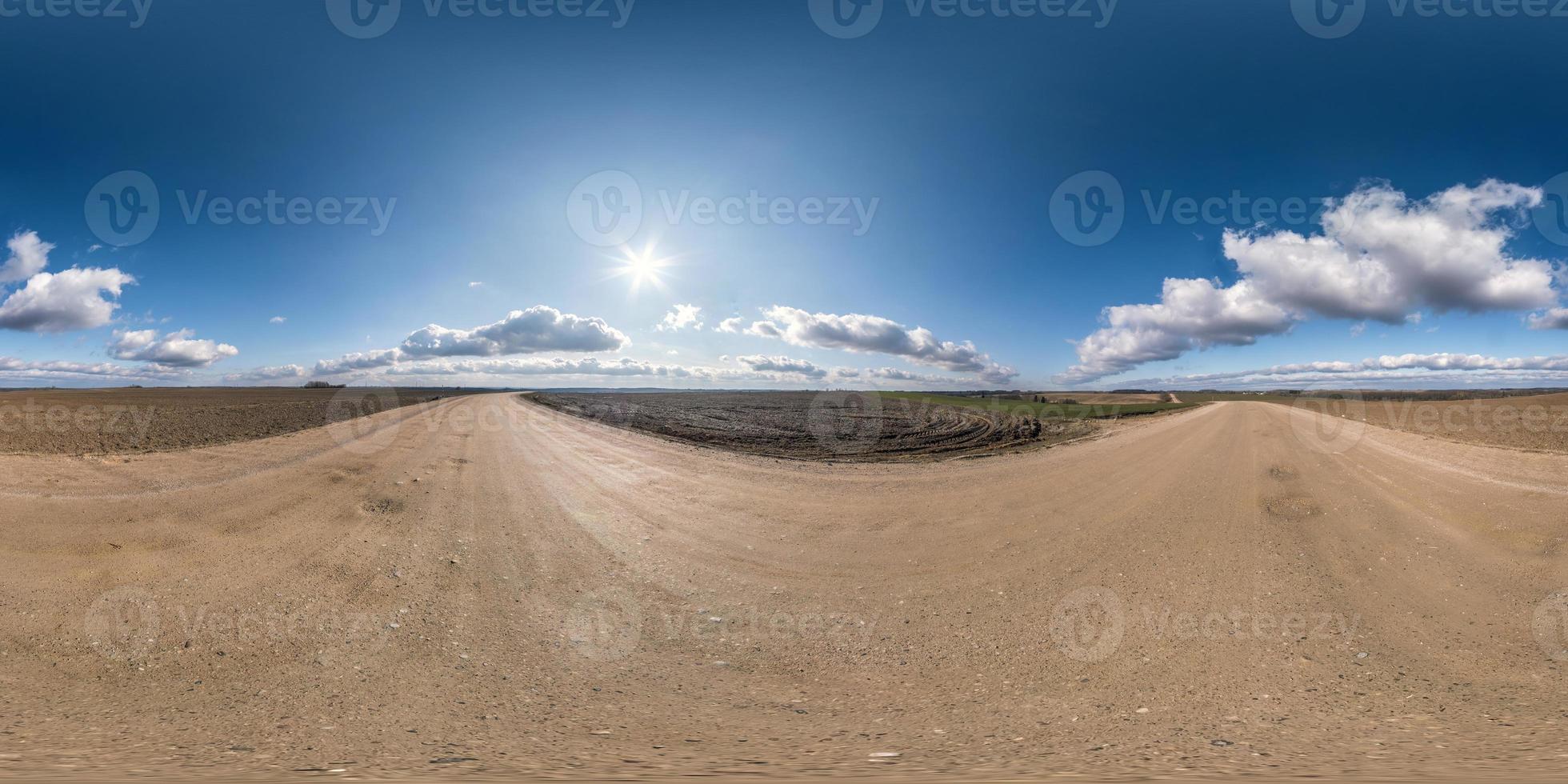 panorama hdri esférico completo sem costura vista de ângulo de 360 graus na estrada de cascalho entre campos no início da primavera com sol no céu claro com halo em projeção equirretangular, pronto para conteúdo vr ar foto