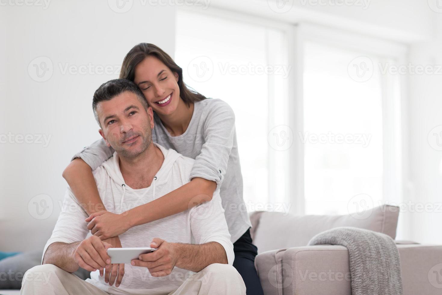 casal feliz usando celular em casa foto