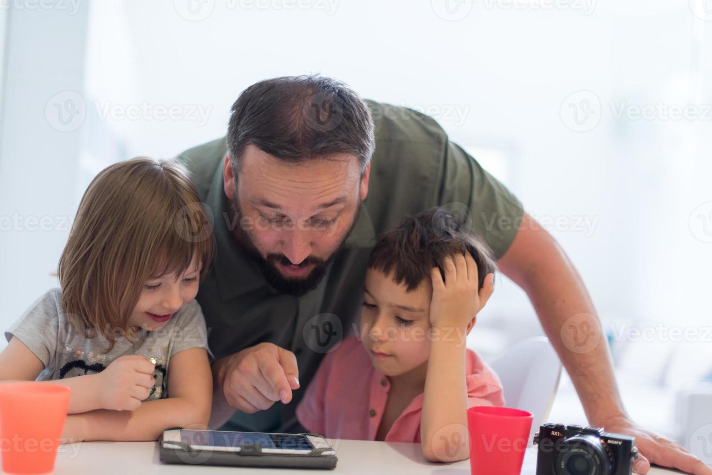 pai solteiro em casa com dois filhos jogando no tablet foto