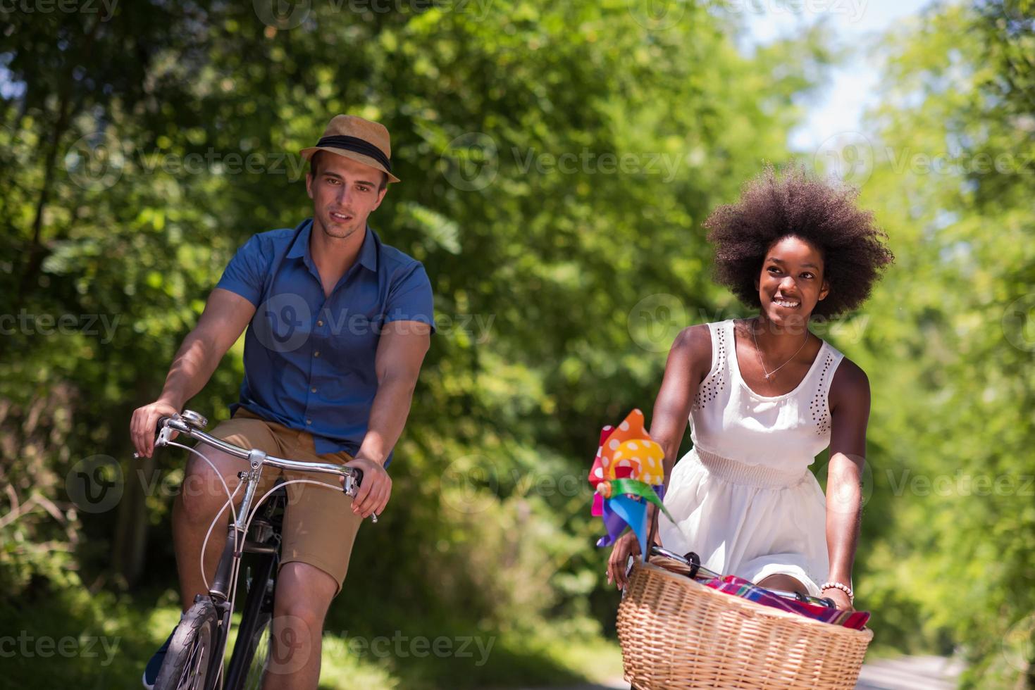 jovem casal multiétnico dando um passeio de bicicleta na natureza foto