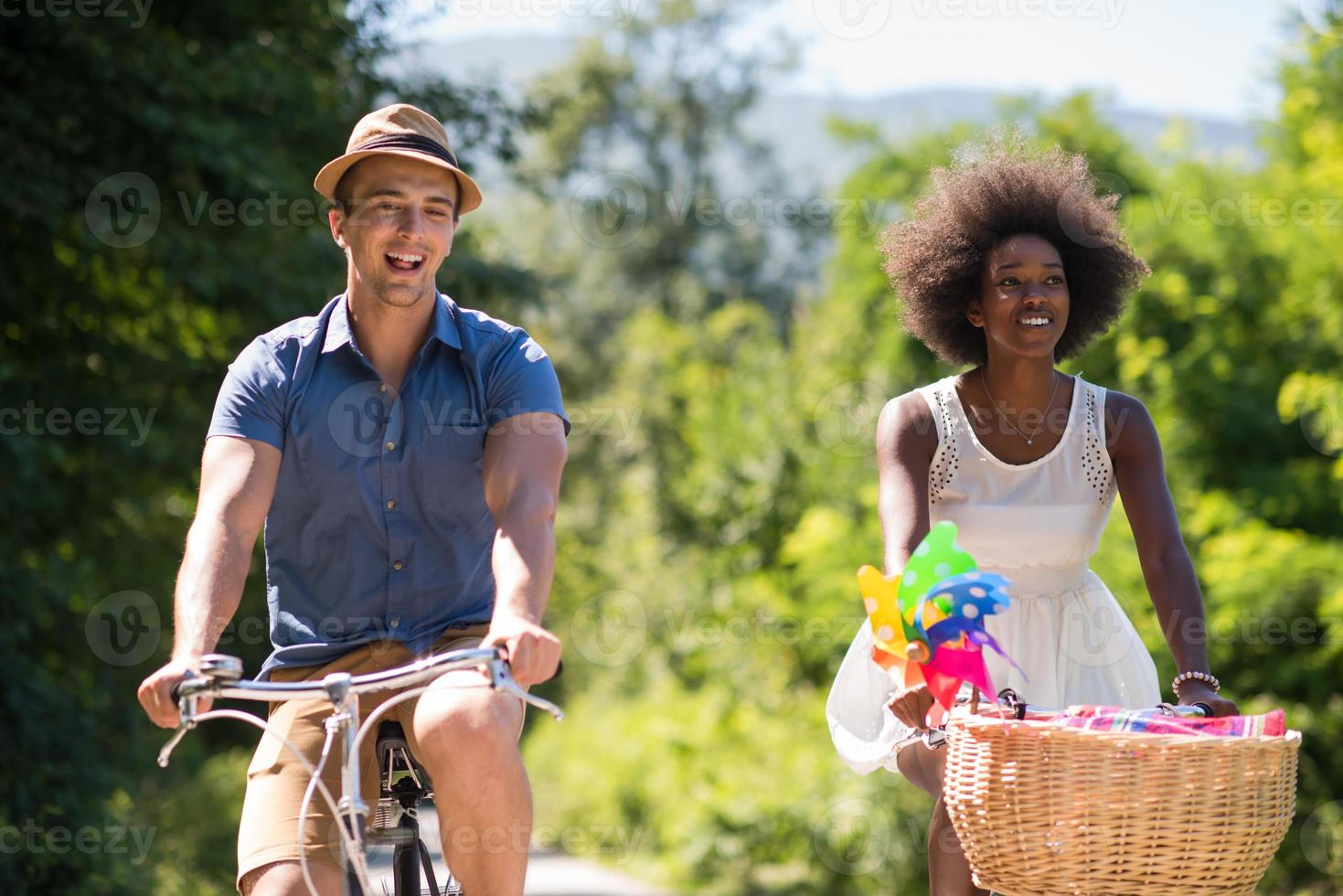 jovem casal multiétnico dando um passeio de bicicleta na natureza foto