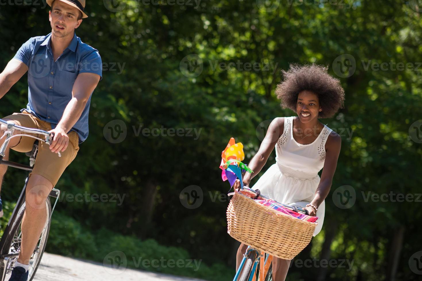 jovem casal multiétnico dando um passeio de bicicleta na natureza foto