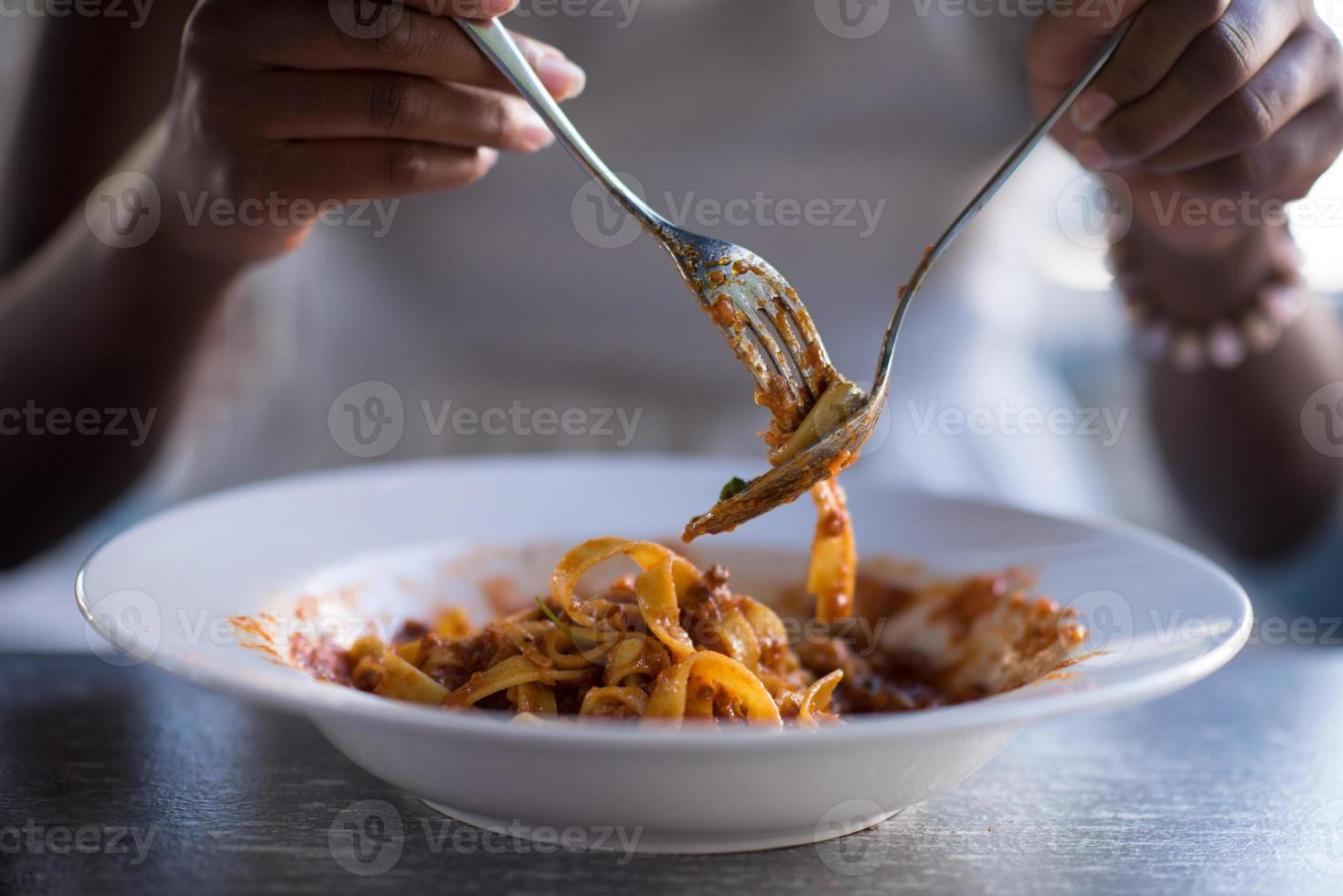 uma jovem afro-americana comendo macarrão foto