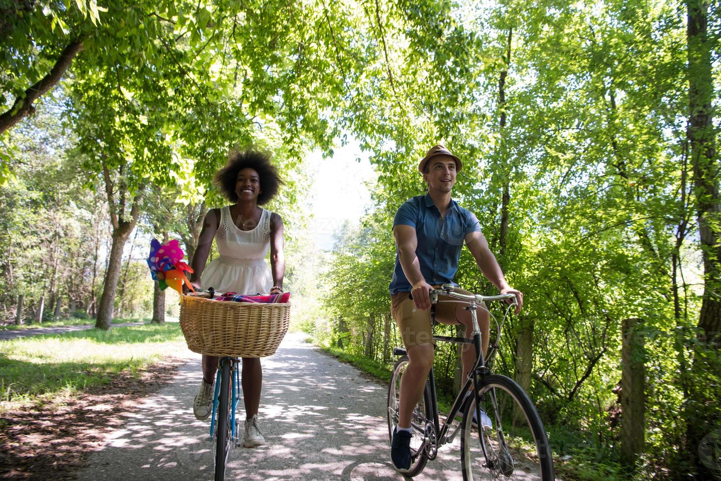 jovem casal multiétnico dando um passeio de bicicleta na natureza foto