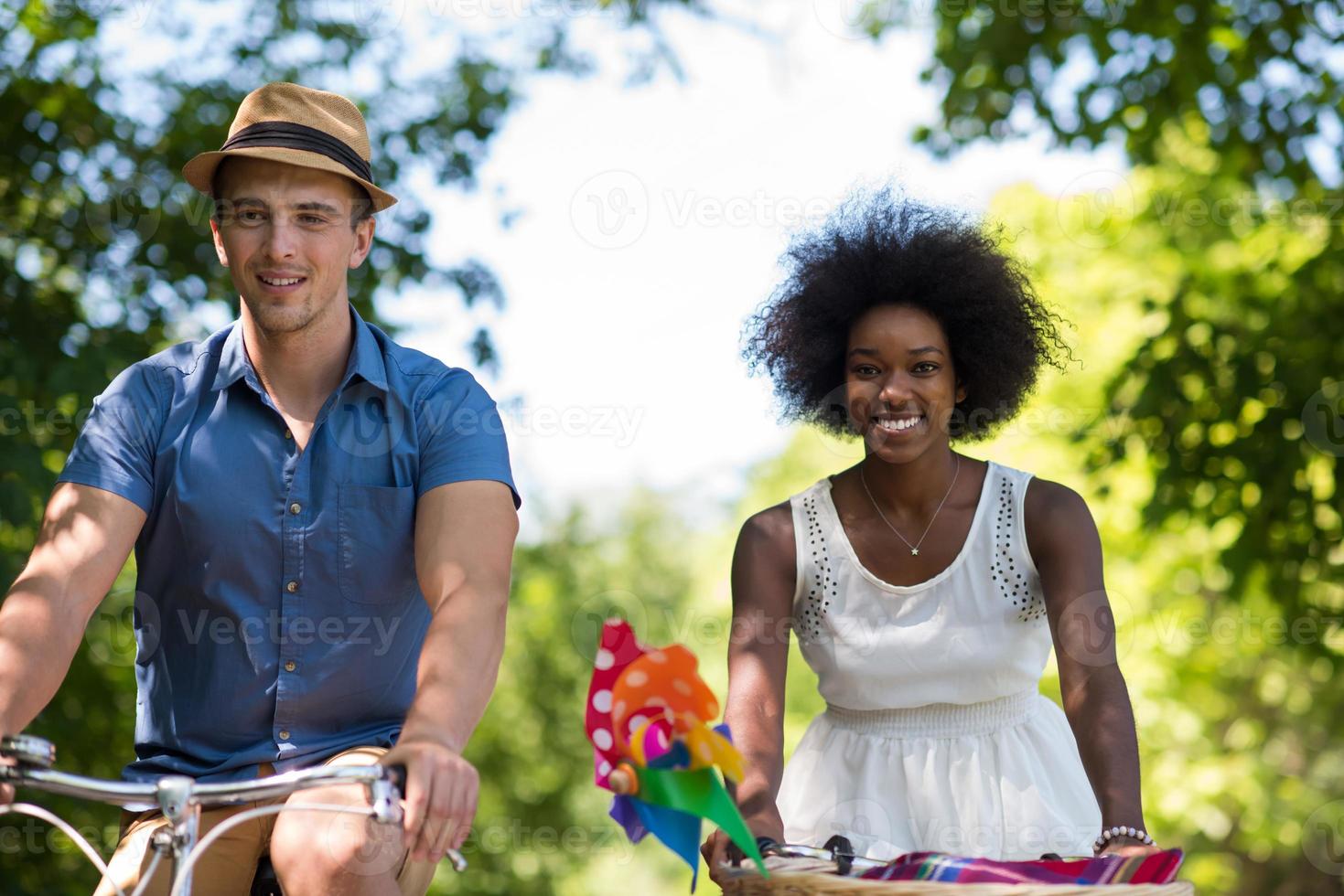 jovem casal multiétnico dando um passeio de bicicleta na natureza foto