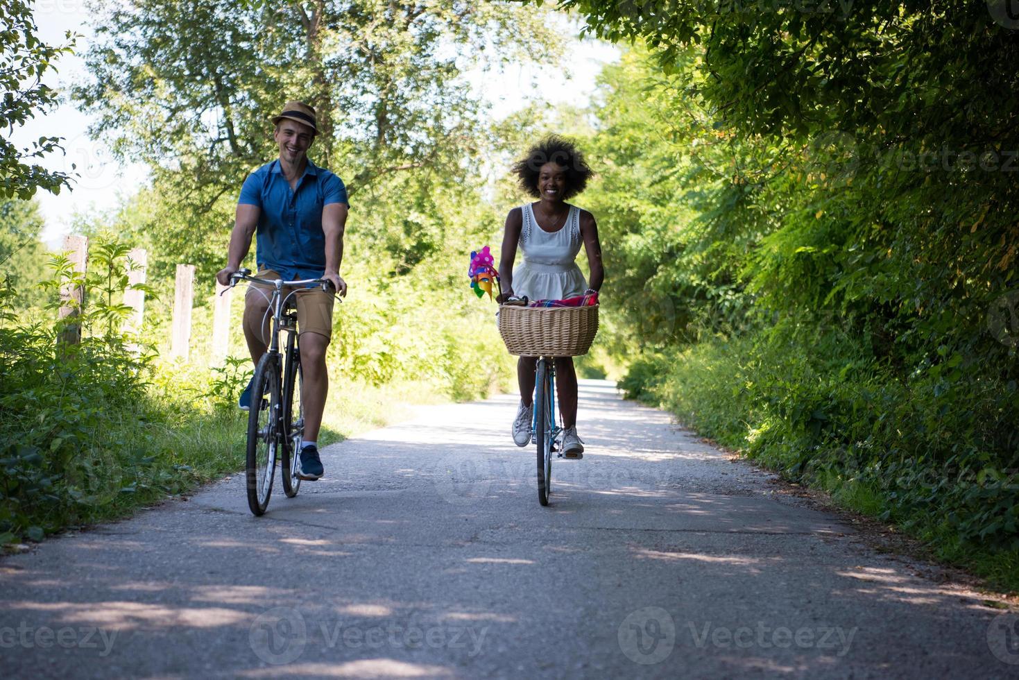 jovem casal multiétnico dando um passeio de bicicleta na natureza foto