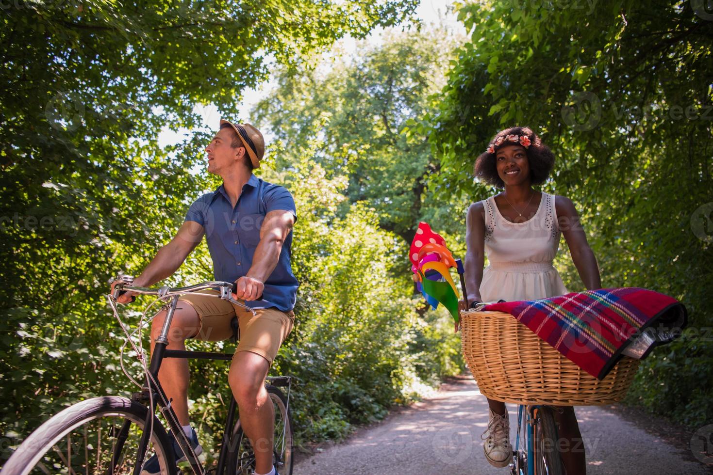 jovem casal multiétnico dando um passeio de bicicleta na natureza foto