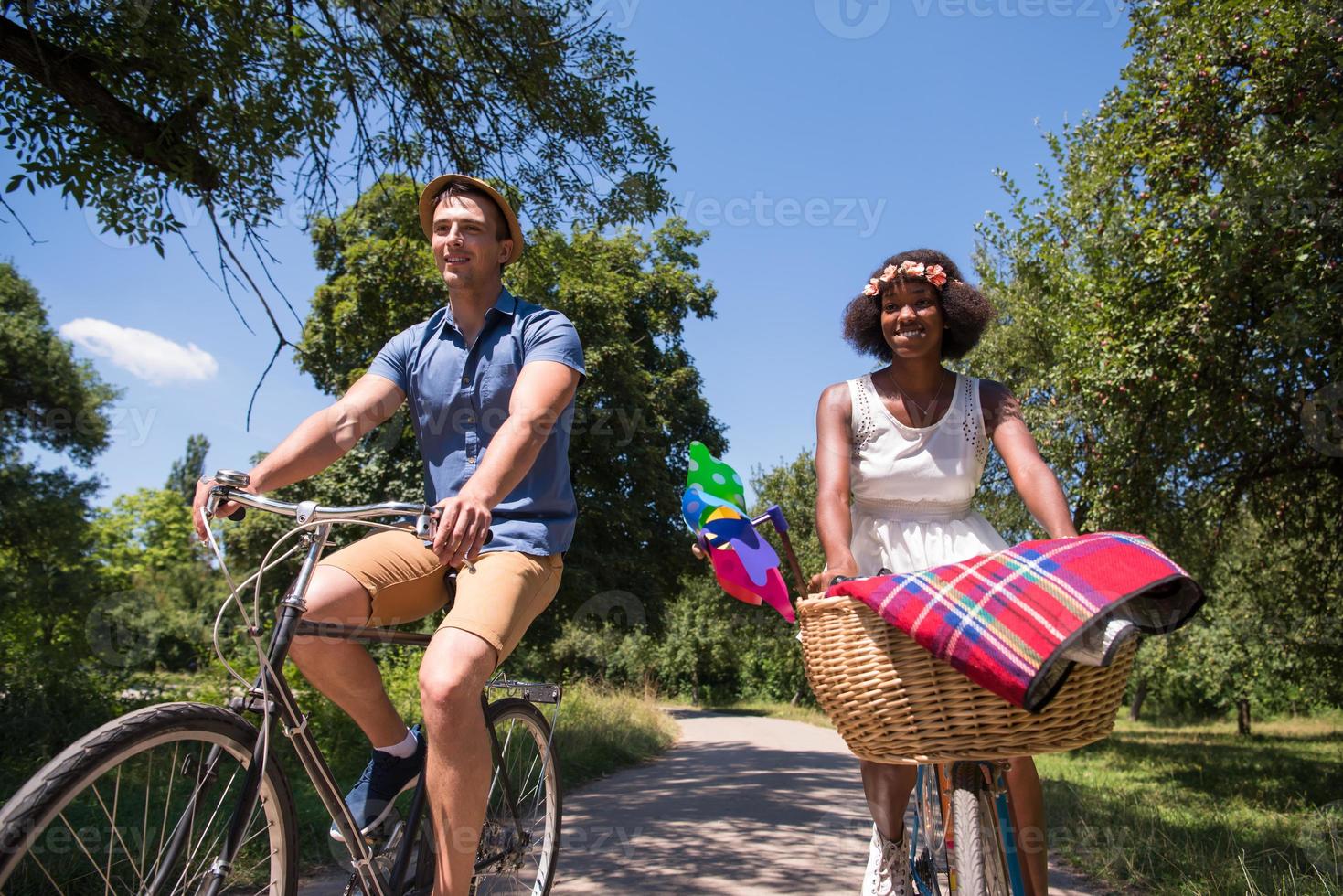 jovem casal multiétnico dando um passeio de bicicleta na natureza foto