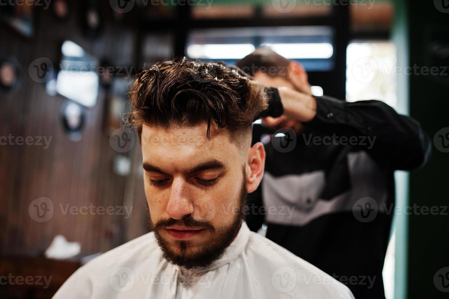 homem barbudo bonito na barbearia, barbeiro no trabalho. foto