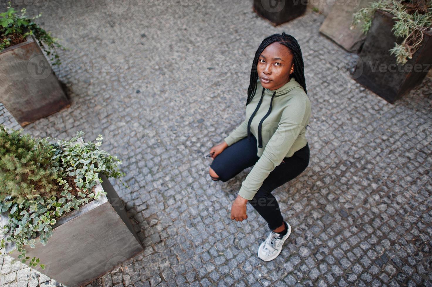 retrato da cidade de uma jovem fêmea de pele escura positiva vestindo capuz verde. foto