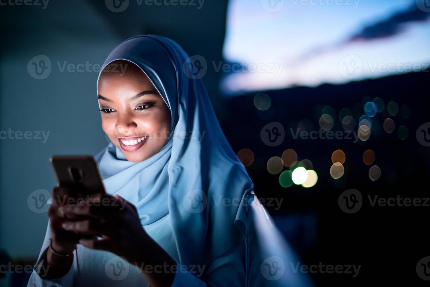 jovem muçulmana na rua à noite usando telefone foto