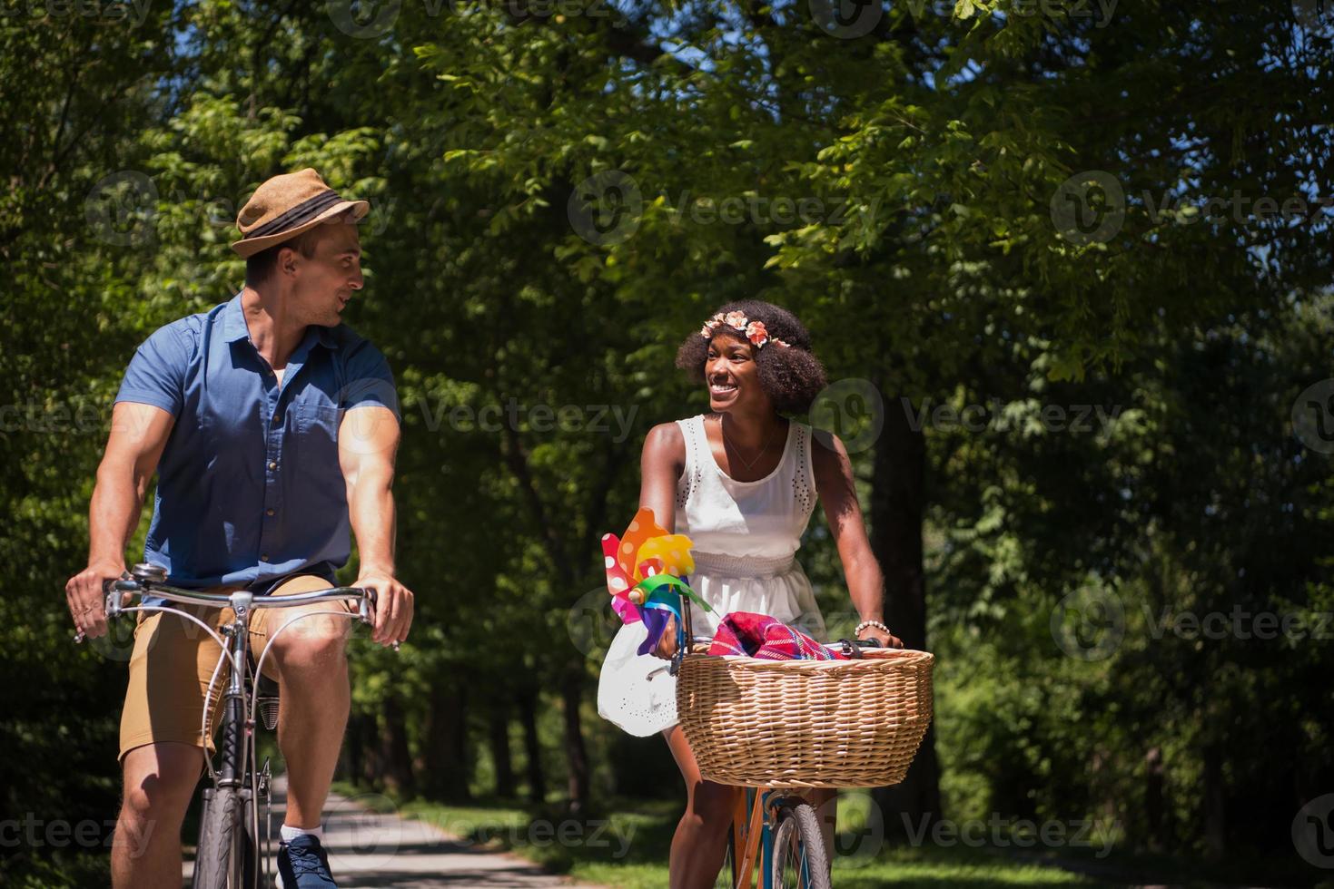 jovem casal multiétnico dando um passeio de bicicleta na natureza foto