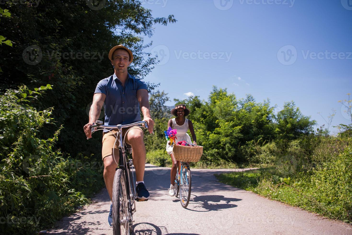 jovem casal multiétnico dando um passeio de bicicleta na natureza foto