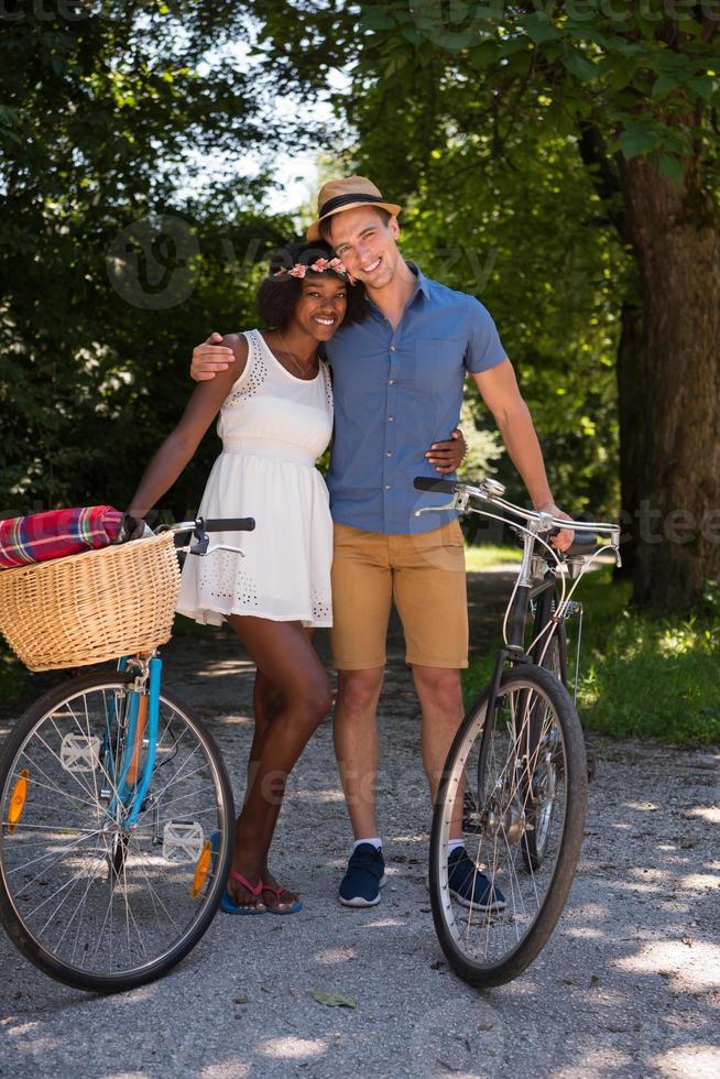 jovem casal multiétnico dando um passeio de bicicleta na natureza foto