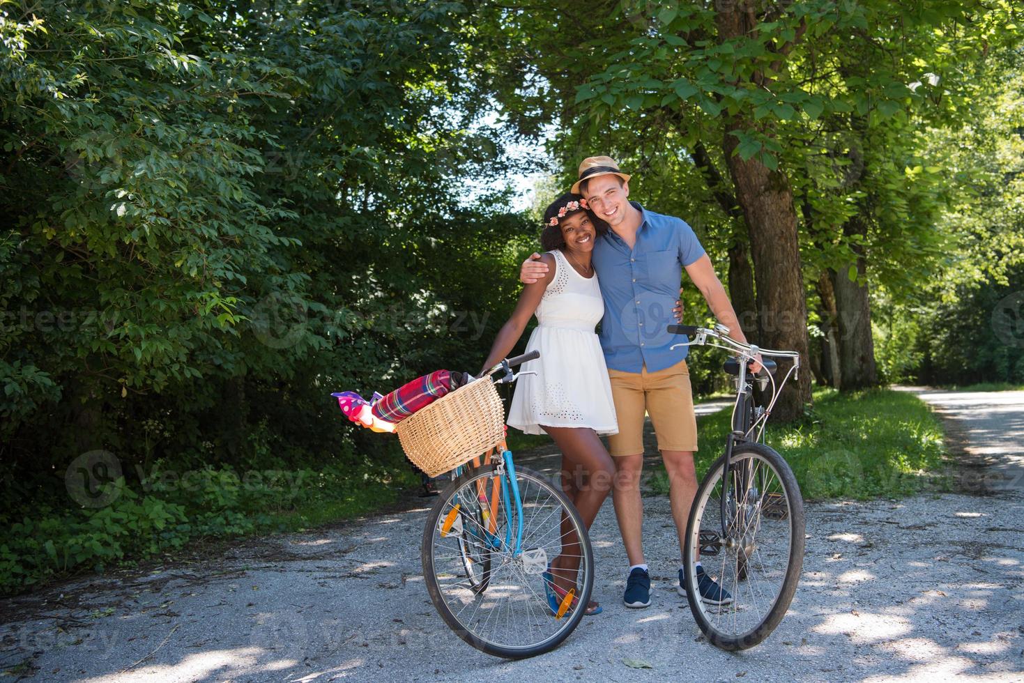 jovem casal multiétnico dando um passeio de bicicleta na natureza foto