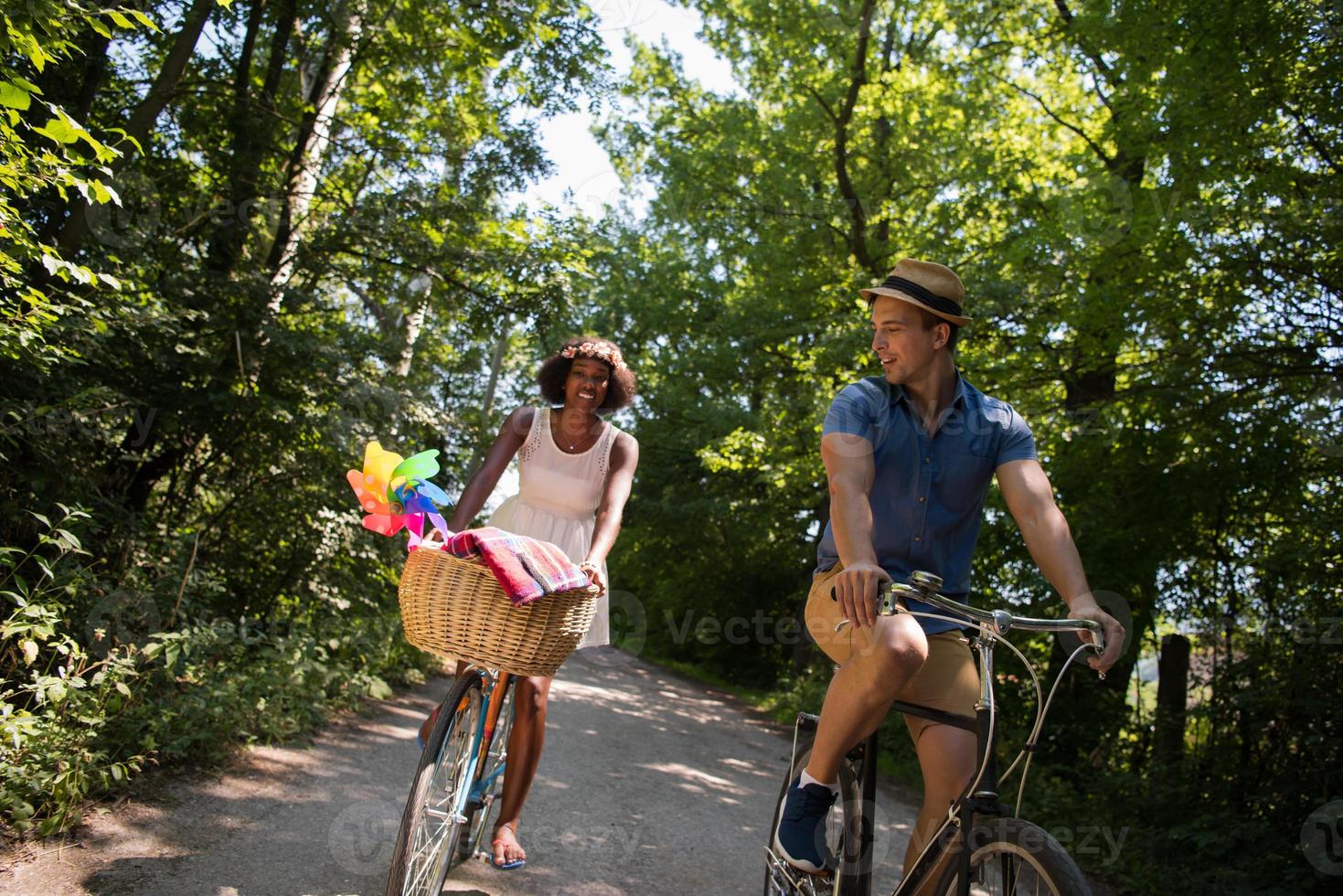 jovem casal multiétnico dando um passeio de bicicleta na natureza foto