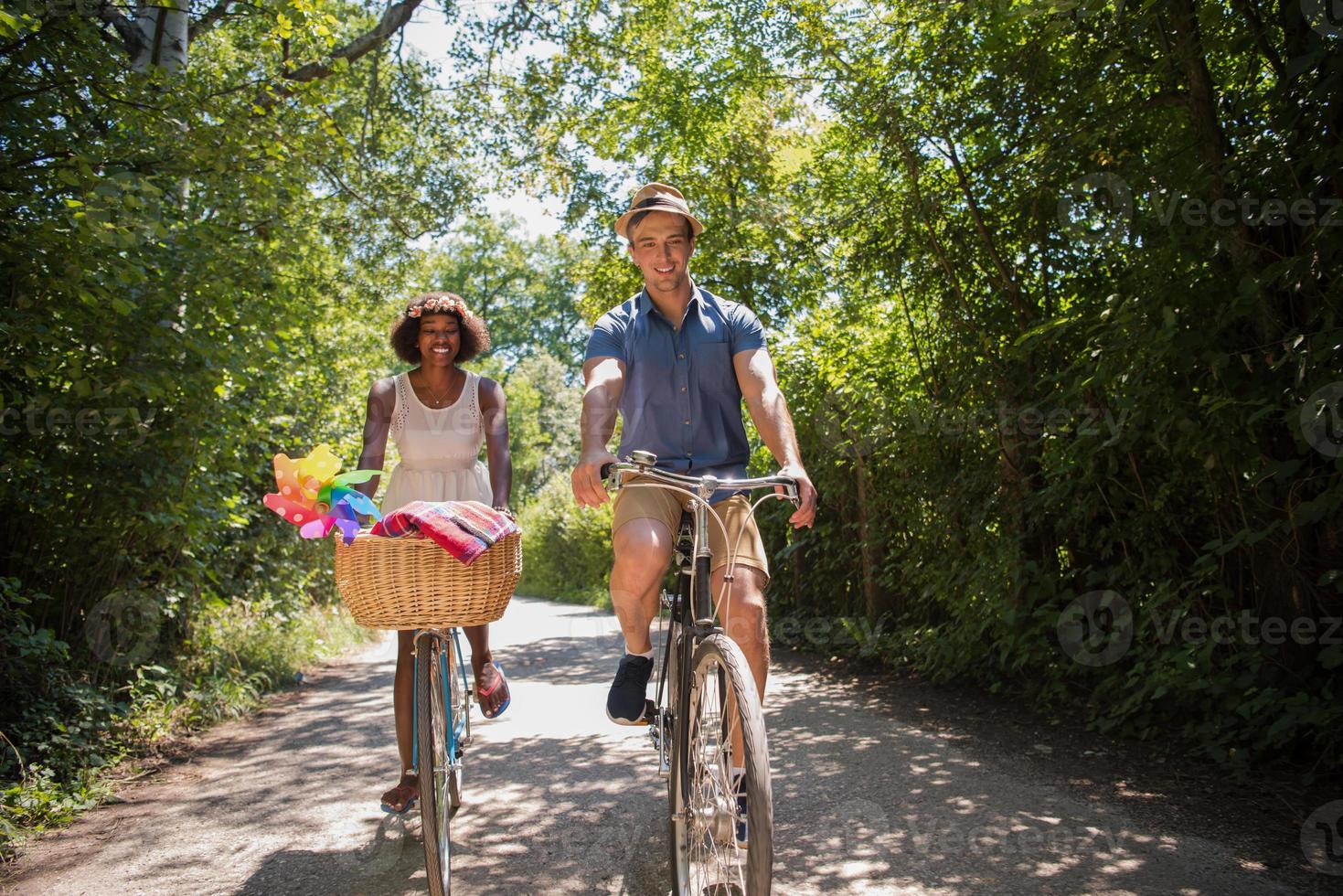 jovem casal multiétnico dando um passeio de bicicleta na natureza foto