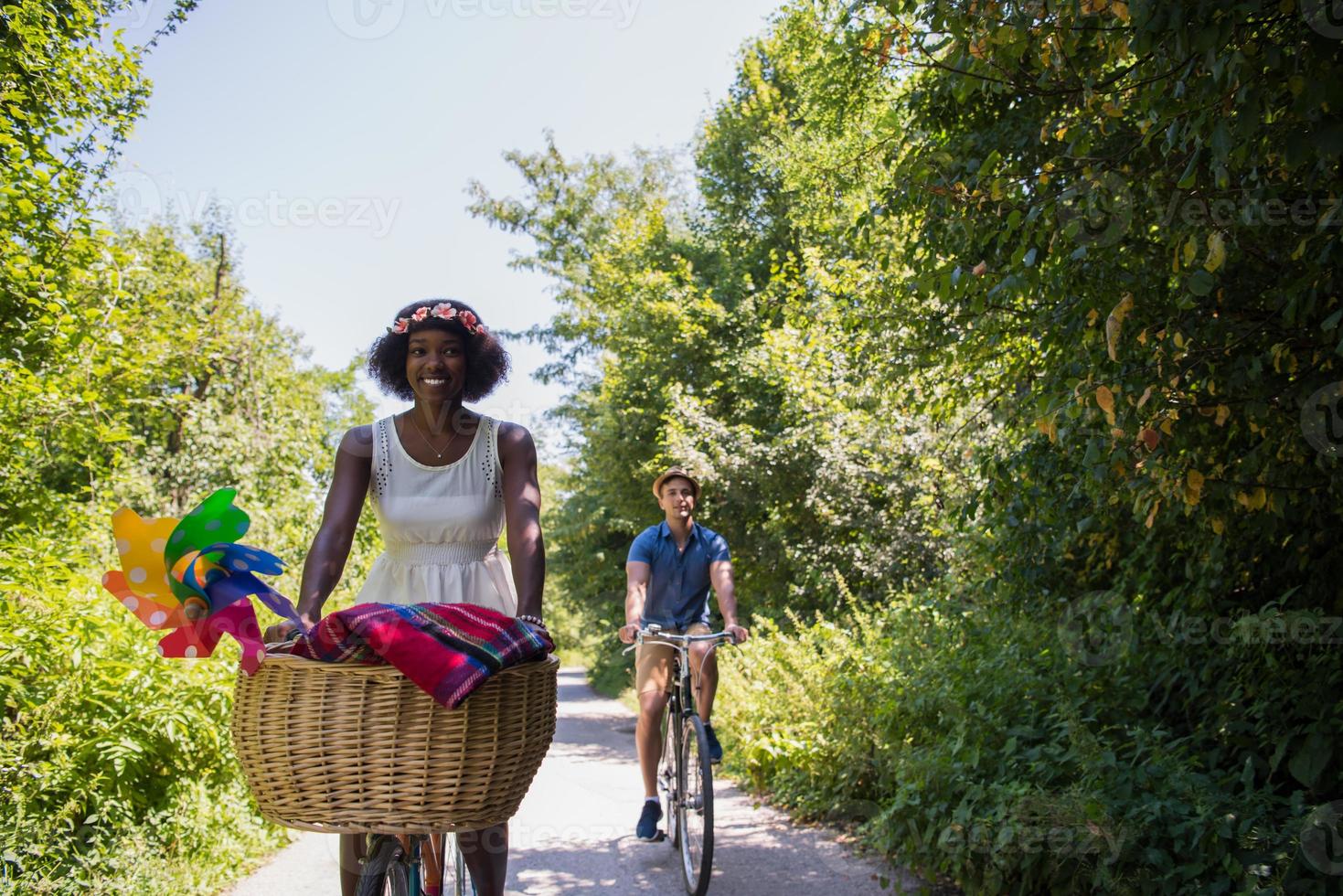 jovem casal multiétnico dando um passeio de bicicleta na natureza foto