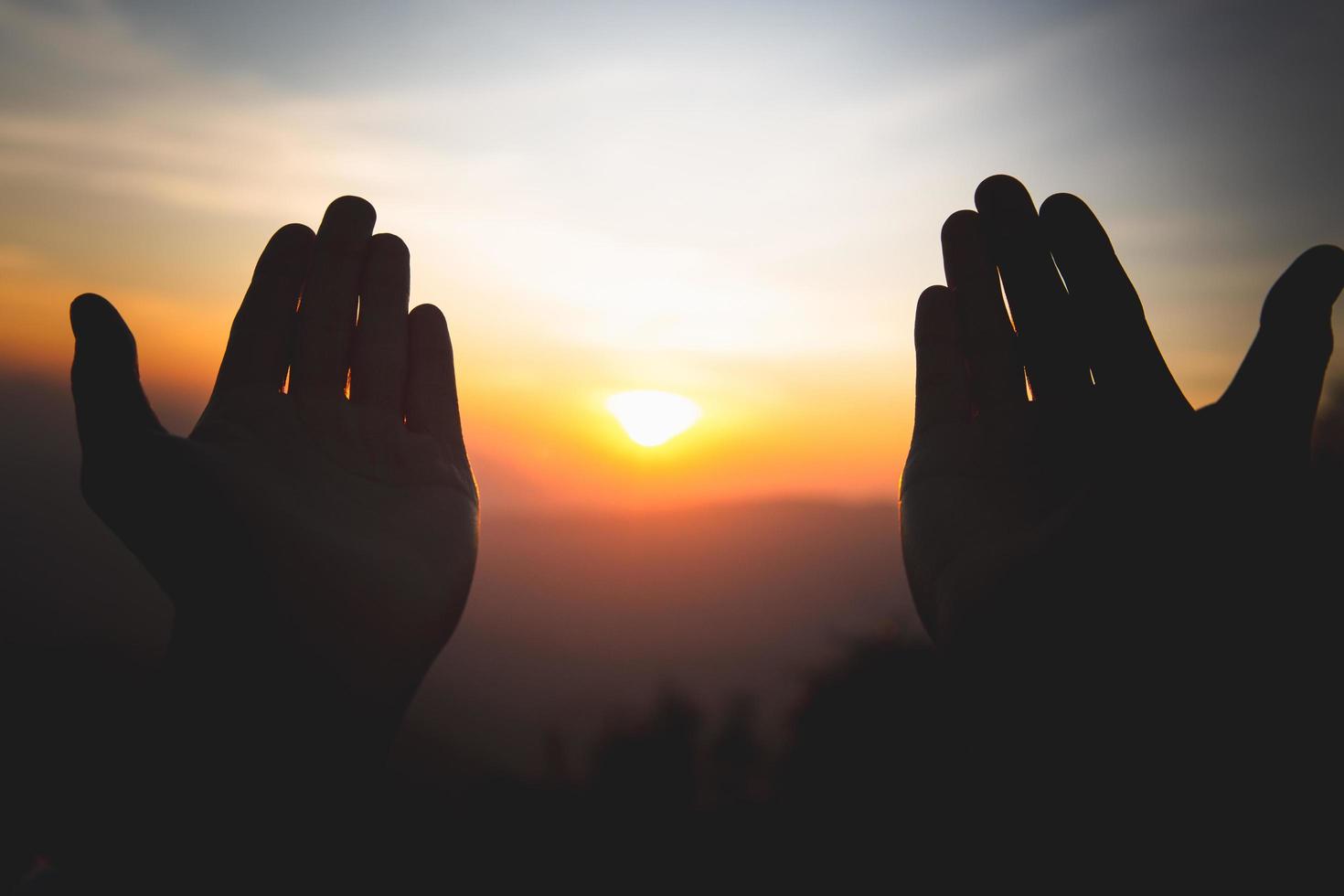 silhueta das mãos do homem cristão orando a Deus, o homem ora pela bênção de Deus para desejar ter uma vida melhor. implorando por perdão e acreditando na bondade, fundo de conceito de religião cristã. foto