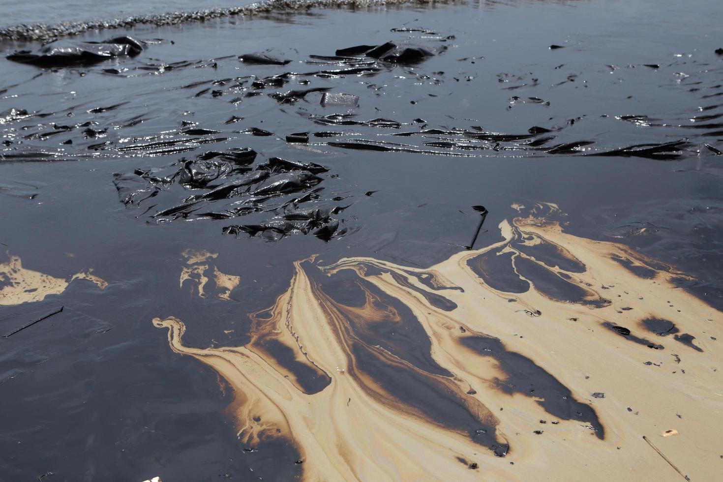 derramamento de petróleo bruto na pedra na praia foto