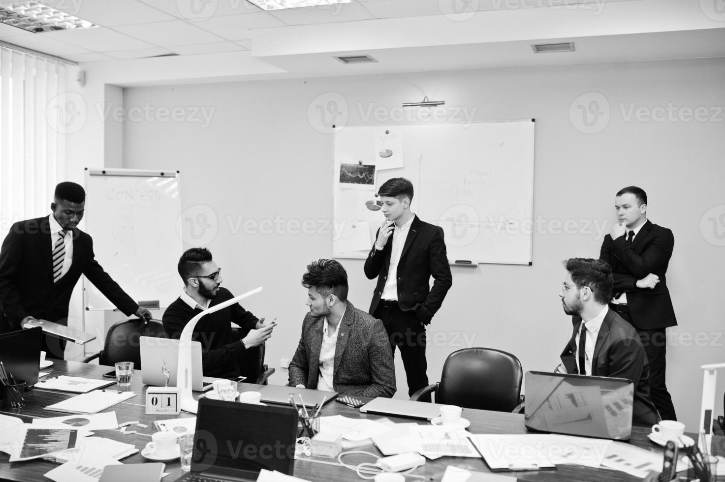 seis homens de negócios multirraciais no escritório à mesa. grupo diversificado de funcionários do sexo masculino em trajes formais discutindo. foto