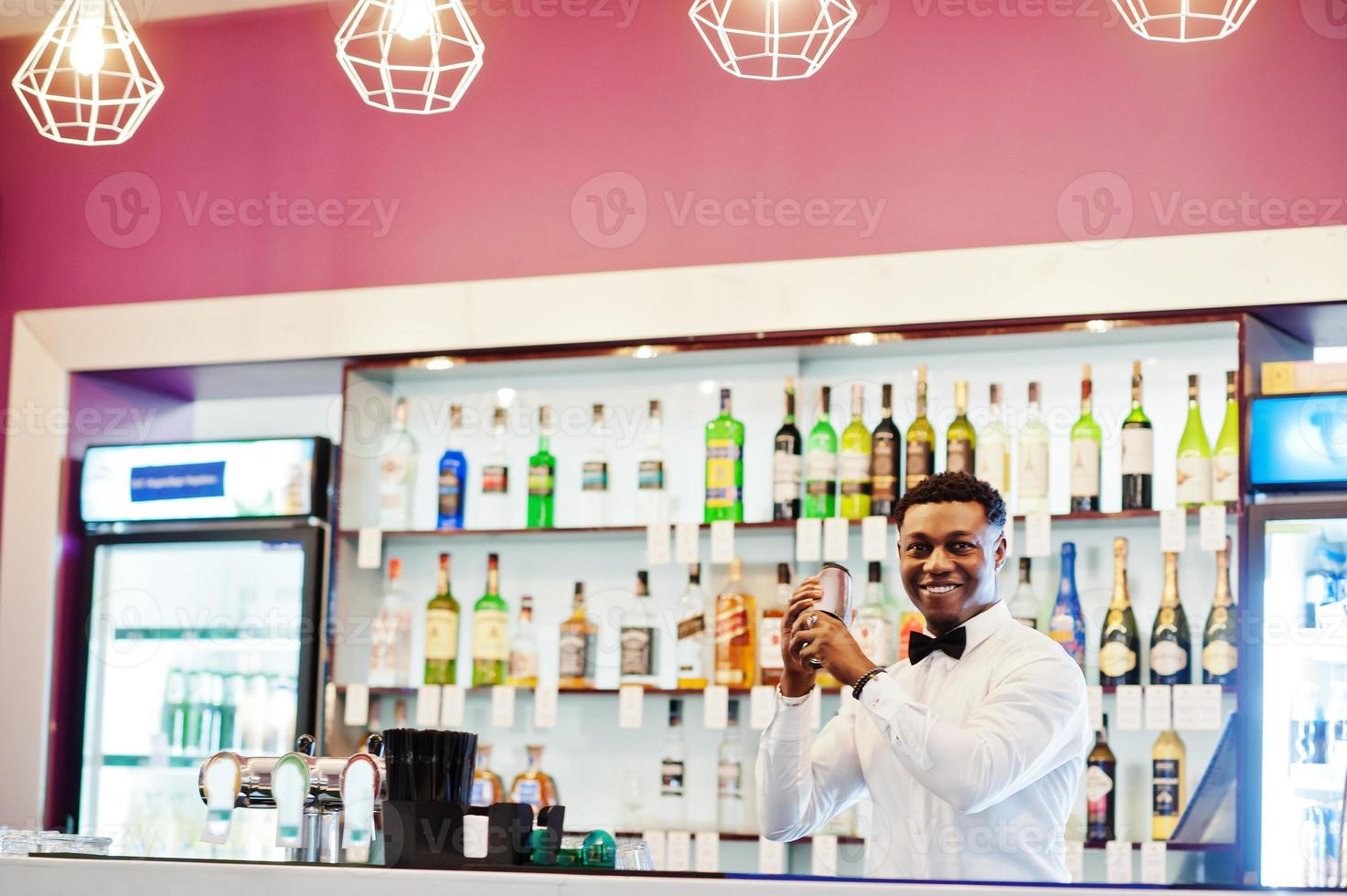 barman americano africano no bar com shaker. preparação de bebidas alcoólicas. foto