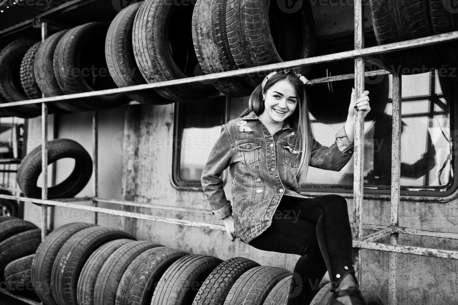 garota jovem hippie na jaqueta jeans e lenço na cabeça na zona de montagem do pneu. foto