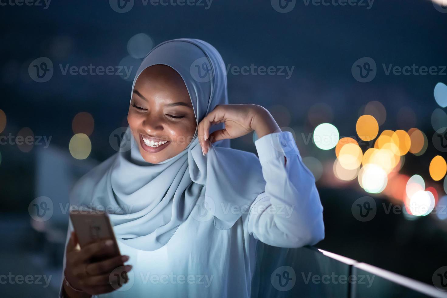 jovem muçulmana na rua à noite usando telefone foto