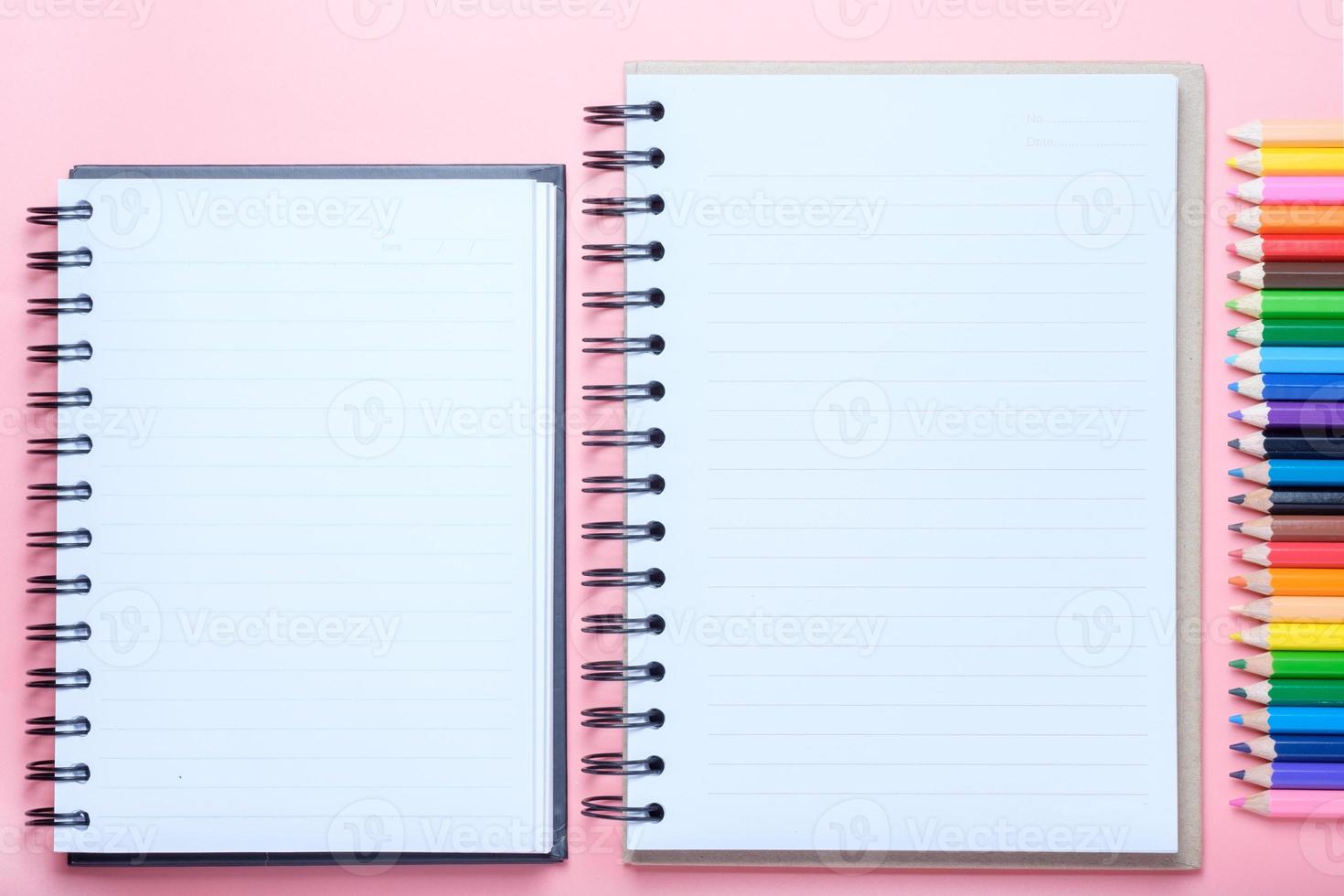 caderno e lápis de cor sobre fundo rosa foto