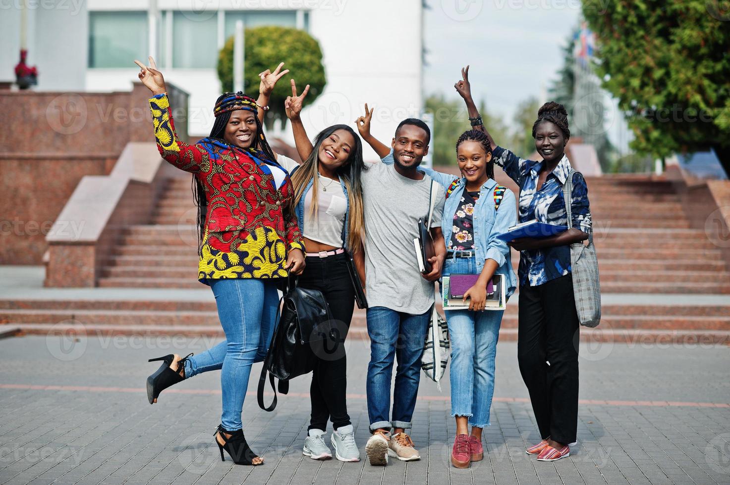 grupo de cinco estudantes universitários africanos passando tempo juntos no campus no pátio da universidade. amigos negros afro estudando. tema educação. foto