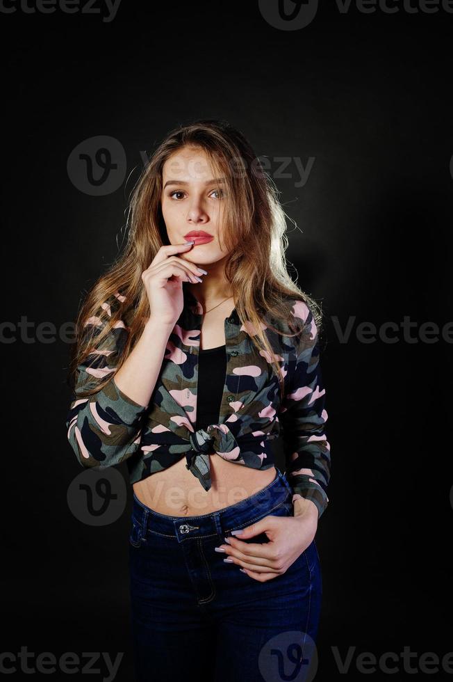 menina morena bonita usa calça jeans e camisa militar, posando no estúdio contra um fundo cinza. retrato de modelo de estúdio. foto