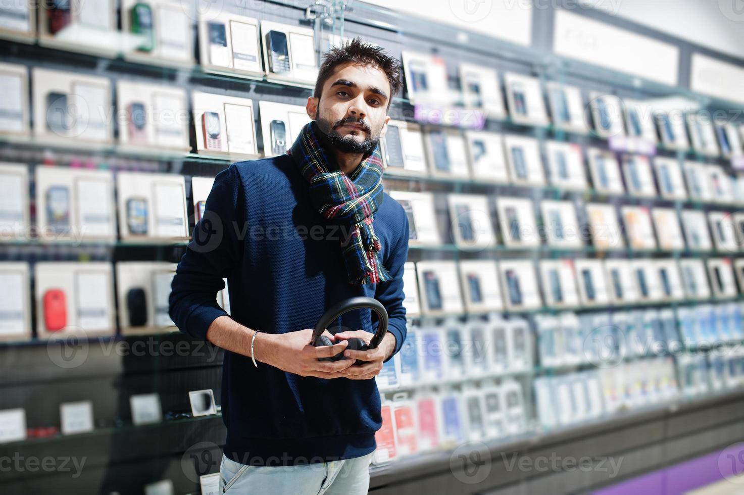 comprador de cliente homem de barba indiana na loja de telefonia móvel com fones de ouvido sem fio. conceito de povos e tecnologias do sul da Ásia. loja de celulares. foto