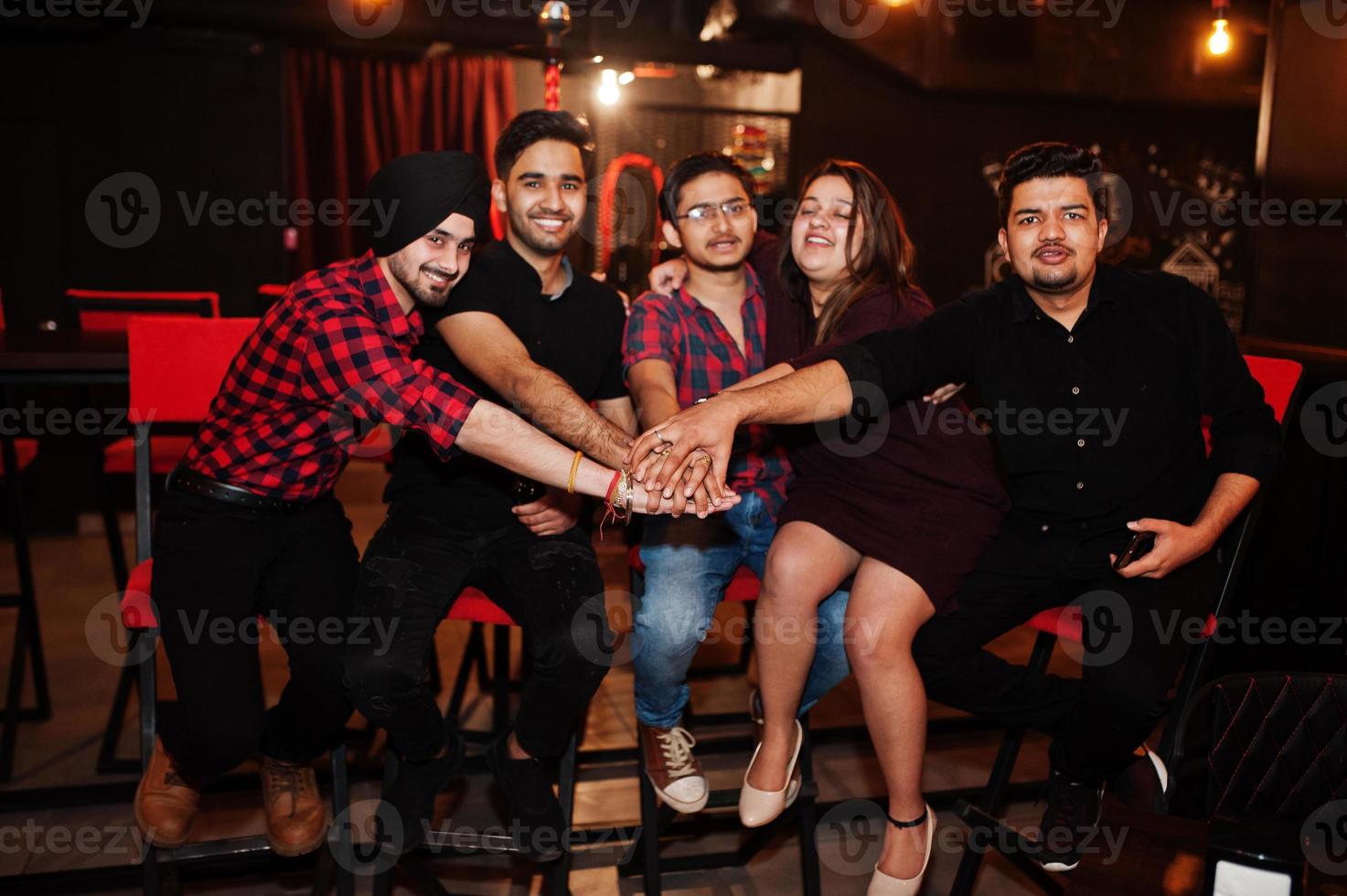 grupo de amigos indianos sentados no lounge bar, se divertindo e descansando. mãos juntas. foto