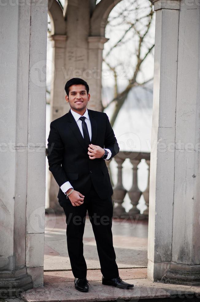 homem de negócios indiano do sul da Ásia elegante em terno preto. Homem de negócios indiano do sul da Ásia elegante em pé de terno preto sob o arco. foto